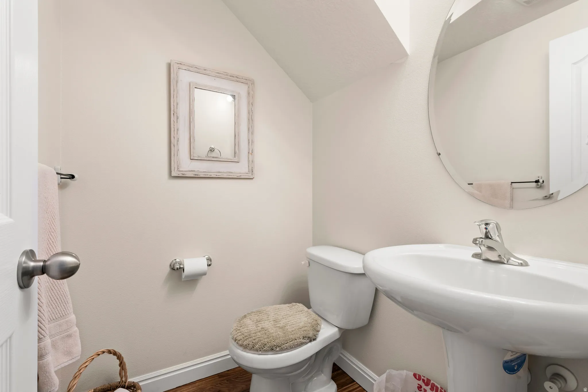 Half bathroom with vaulted ceiling and wood finished floors