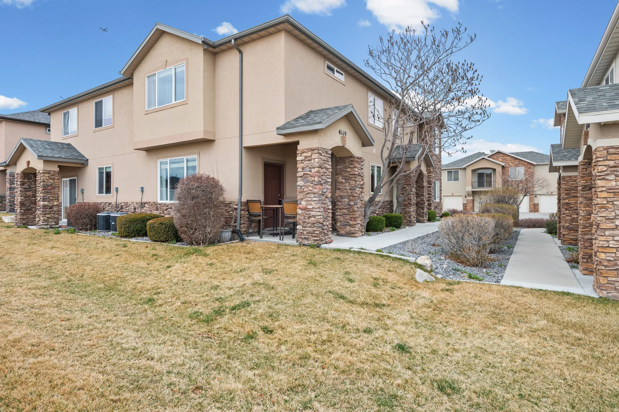 View of front of house with stucco siding, stone siding, and a front yard