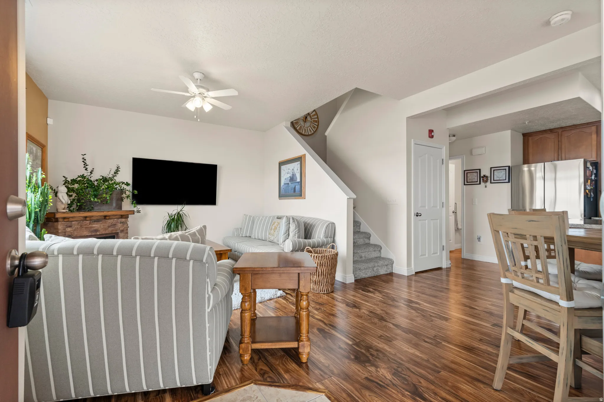 Living area featuring dark wood-style flooring, a ceiling fan, and a textured ceiling
