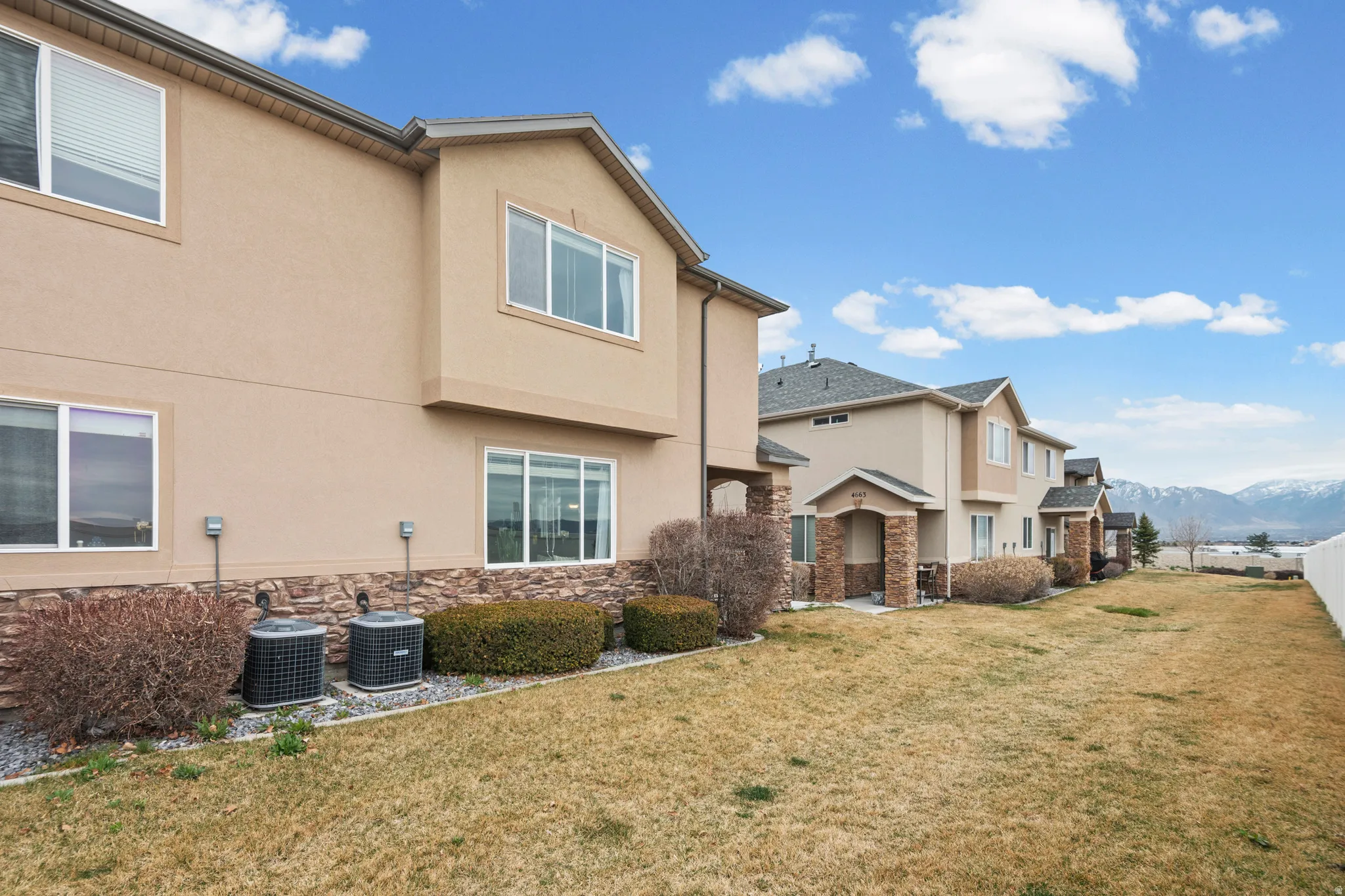 Rear view of property featuring a mountain view, stucco siding, a yard, stone siding, and a patio area