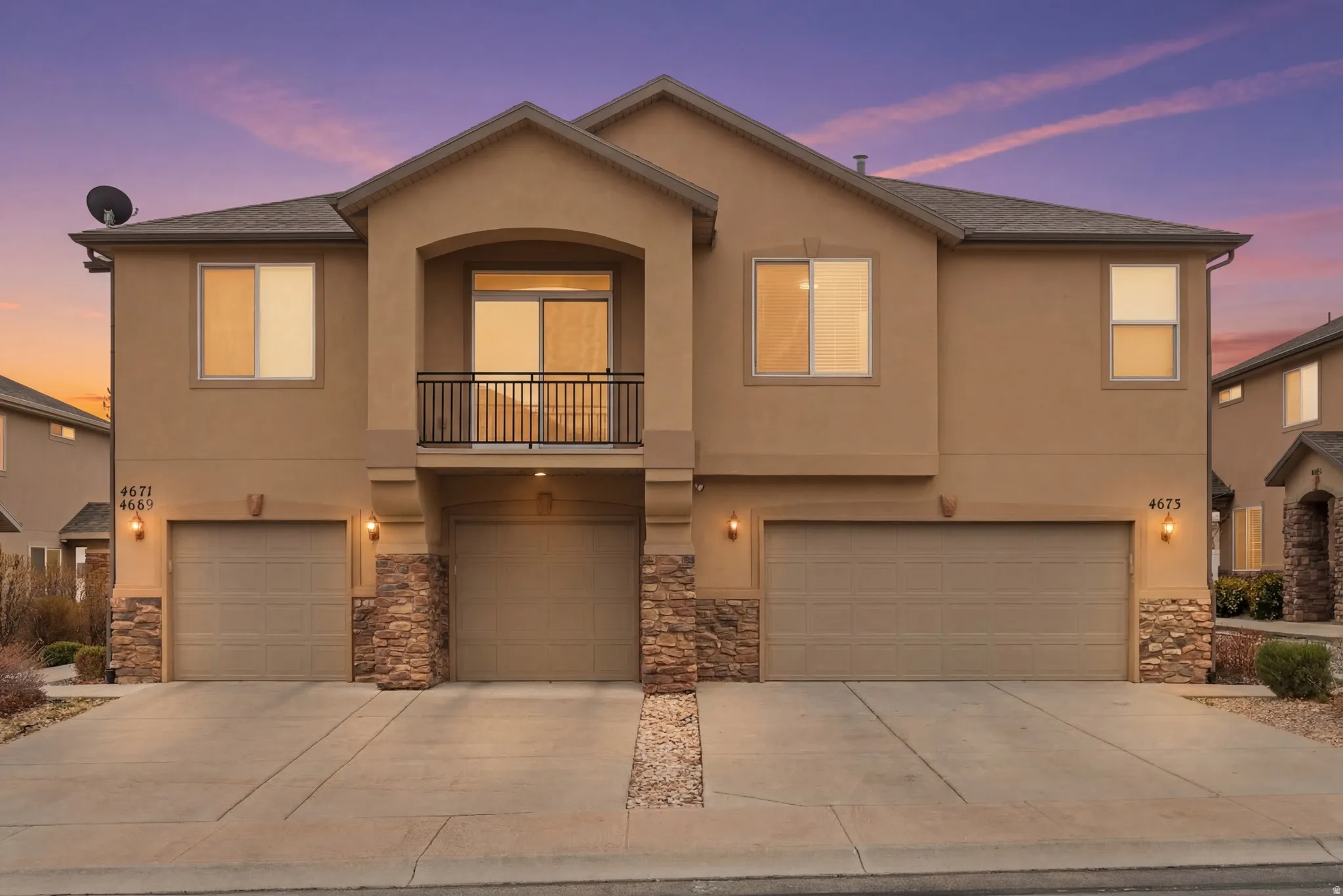 View of front of home with a balcony, stone siding, and a garage