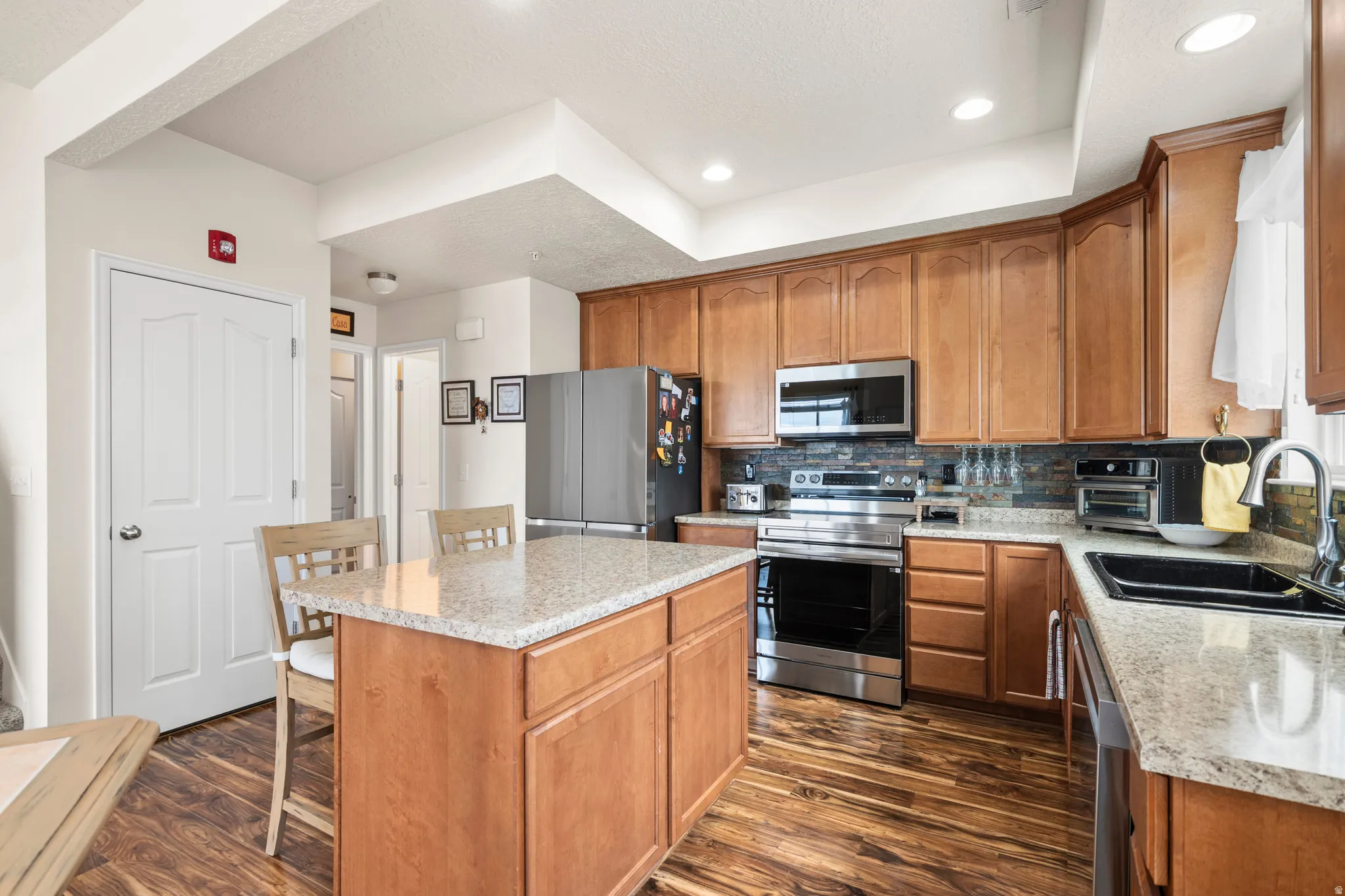 Kitchen featuring a center island, wood finish cabinets, stainless steel appliances, decorative backsplash, and recessed lighting
