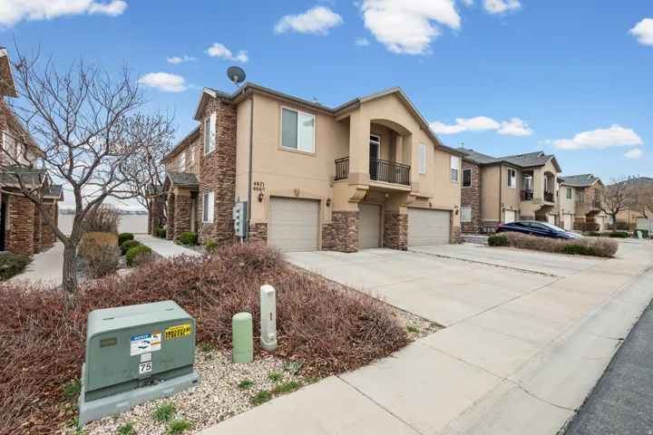View of front of property featuring a garage, stone siding, stucco siding, and driveway
