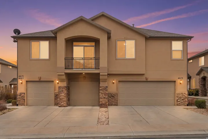 View of front of home with a balcony, stone siding, and a garage