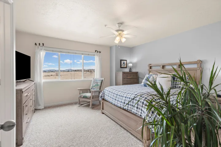 Bedroom with light colored carpet, ceiling fan, and a textured ceiling