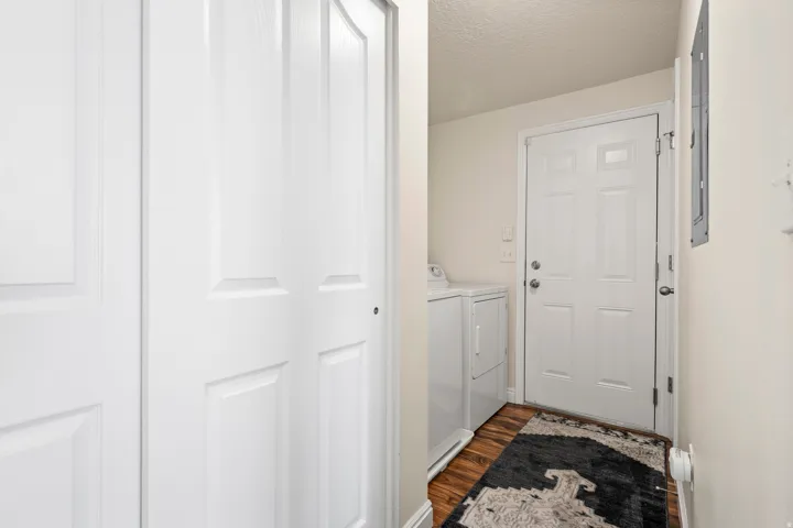 Laundry area with dark wood-type flooring, a textured ceiling, and washing machine and clothes dryer
