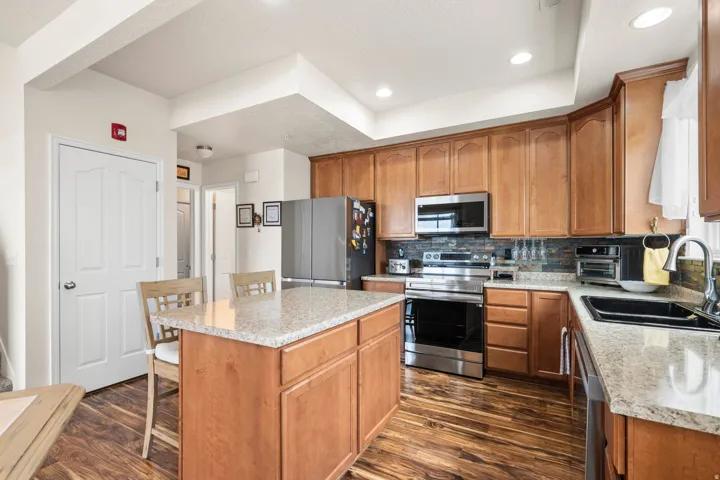 Kitchen featuring a center island, wood finish cabinets, stainless steel appliances, decorative backsplash, and recessed lighting