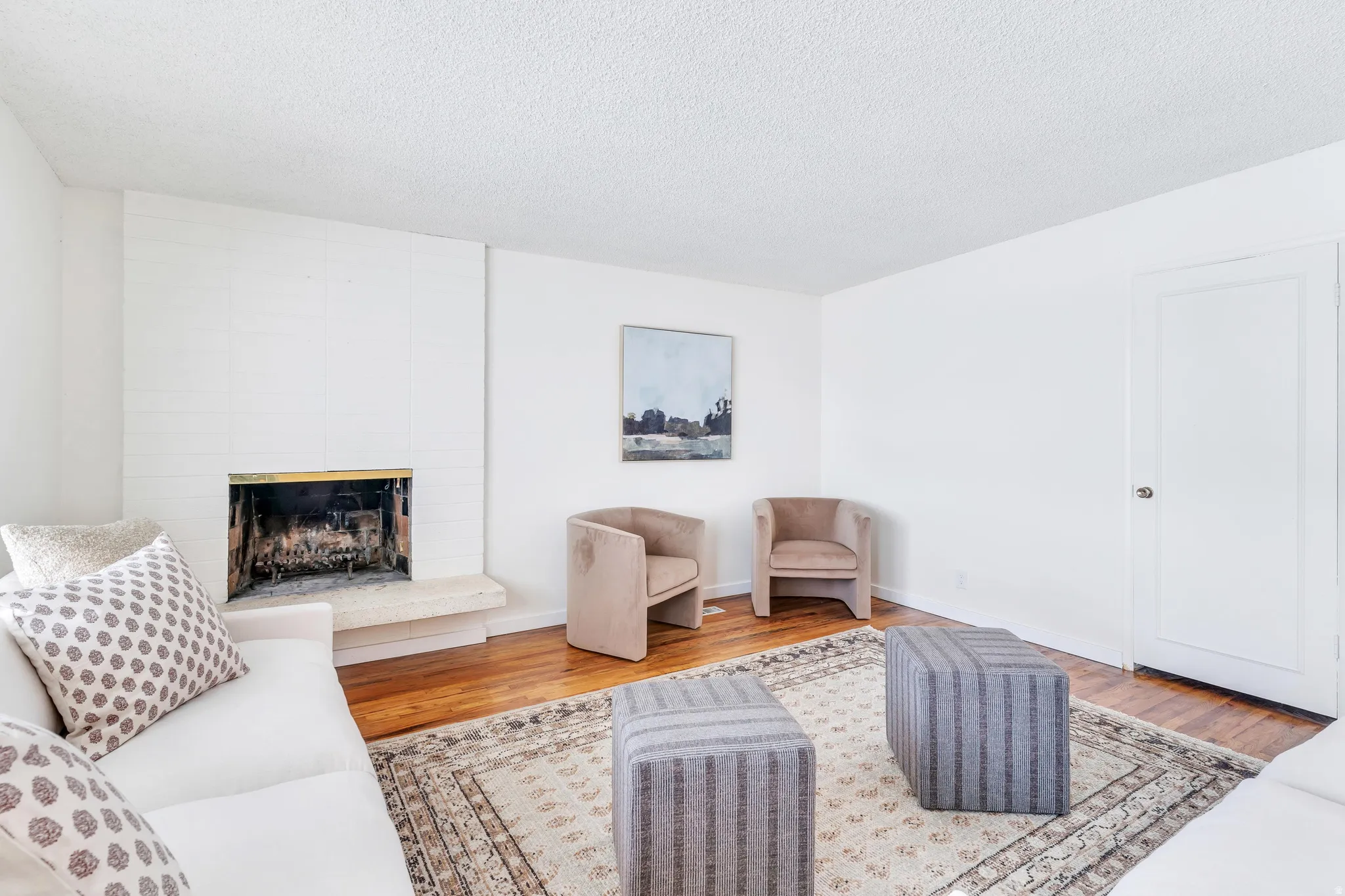 Living room featuring light wood finished floors, a large fireplace, and a textured ceiling