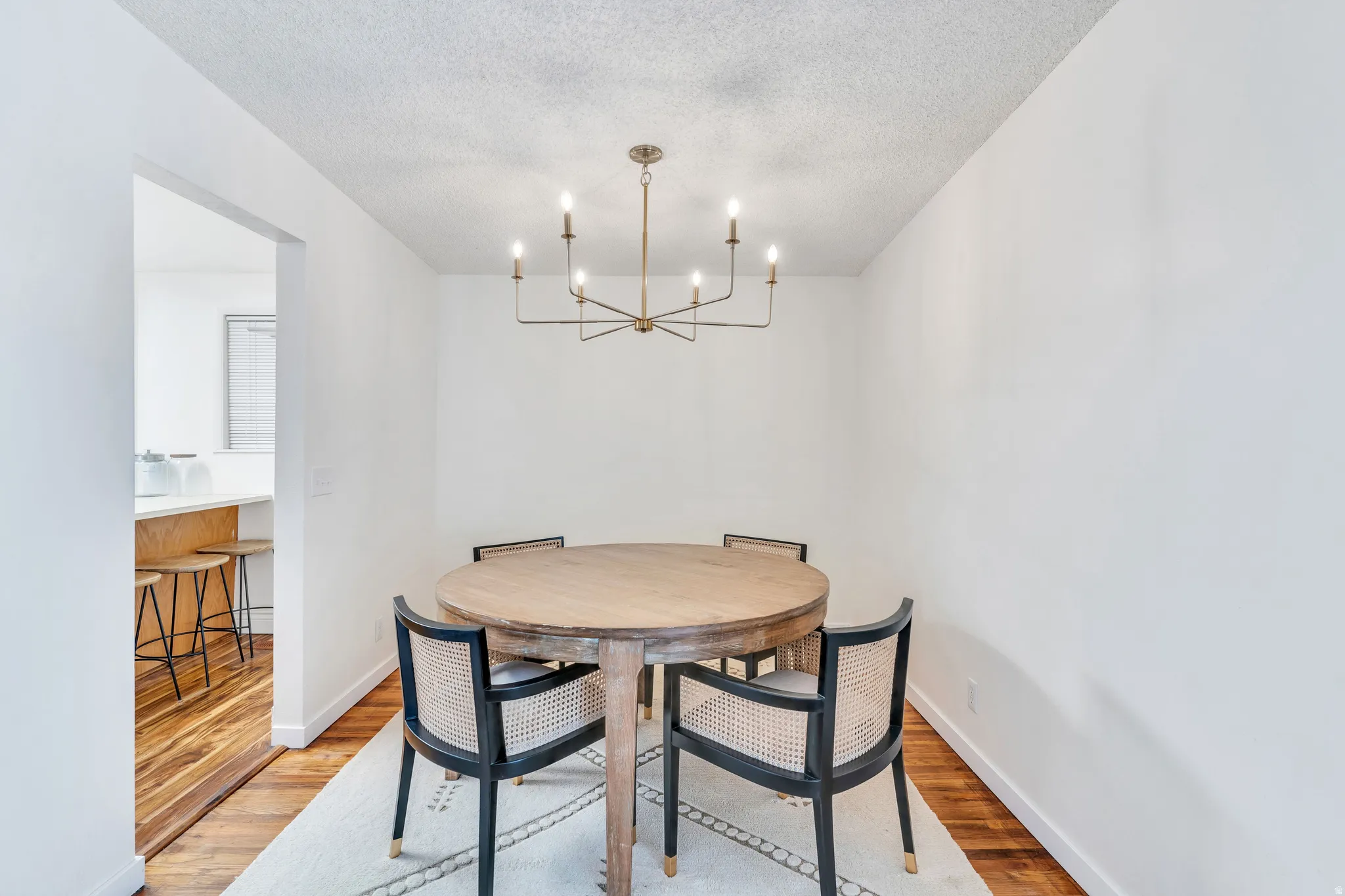 Dining area featuring light wood-style flooring, hanging lights, and a textured ceiling