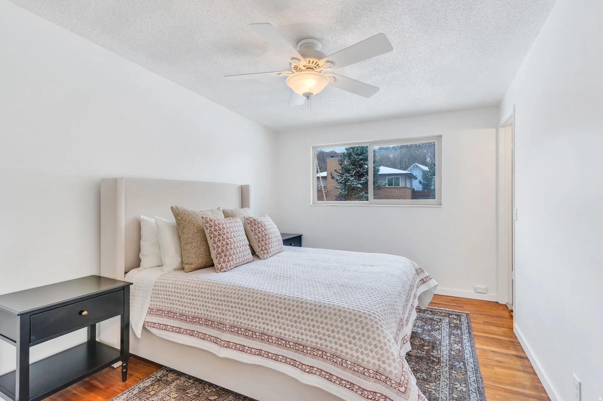 Bedroom with light wood finished floors, ceiling fan, and a textured ceiling