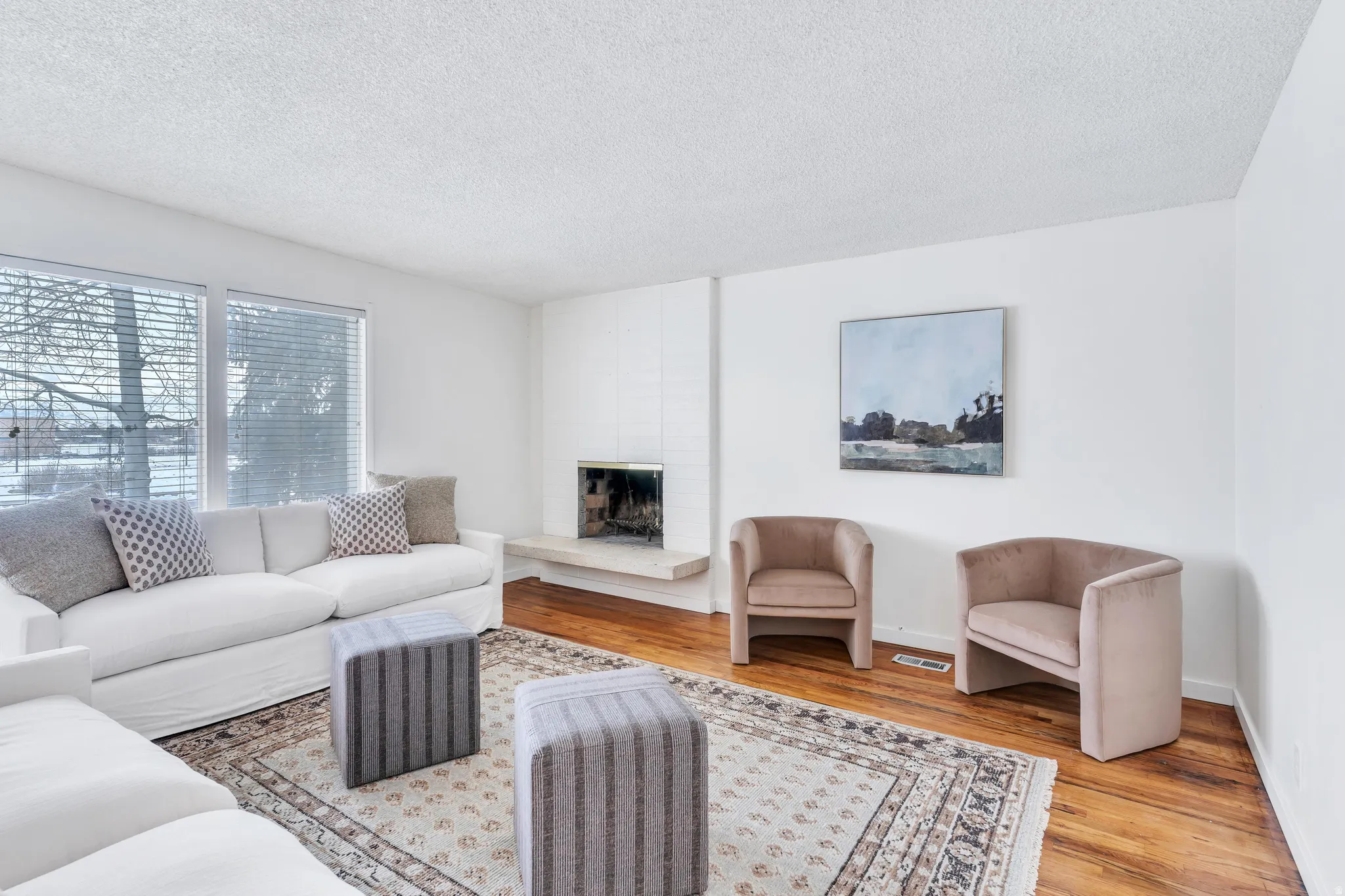Living area with a large fireplace, light wood-style flooring, and a textured ceiling