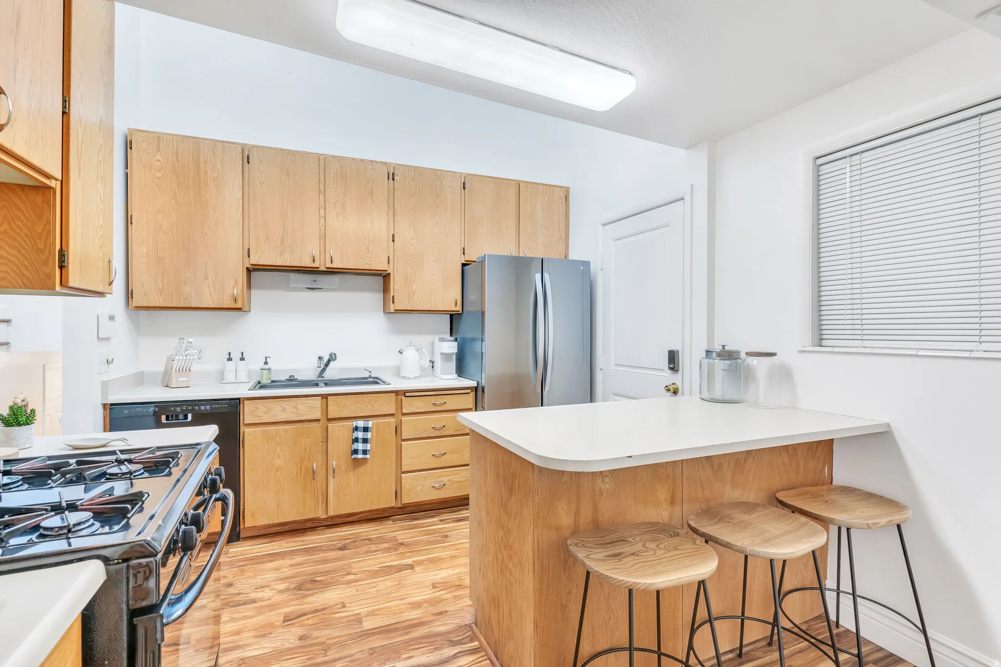 Kitchen with a breakfast bar, gas stove, light countertops, a peninsula, and light wood finished floors