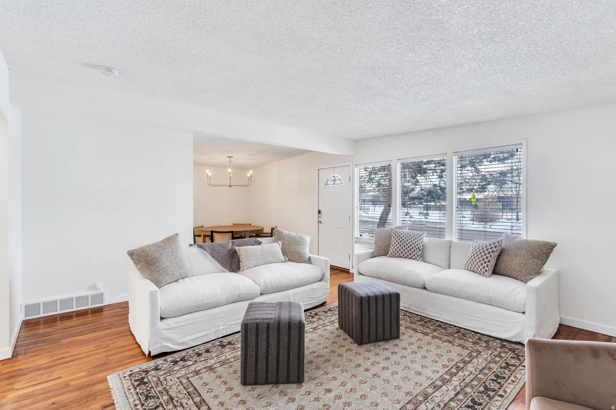 Living room with wood finished floors, hanging lights, and a textured ceiling