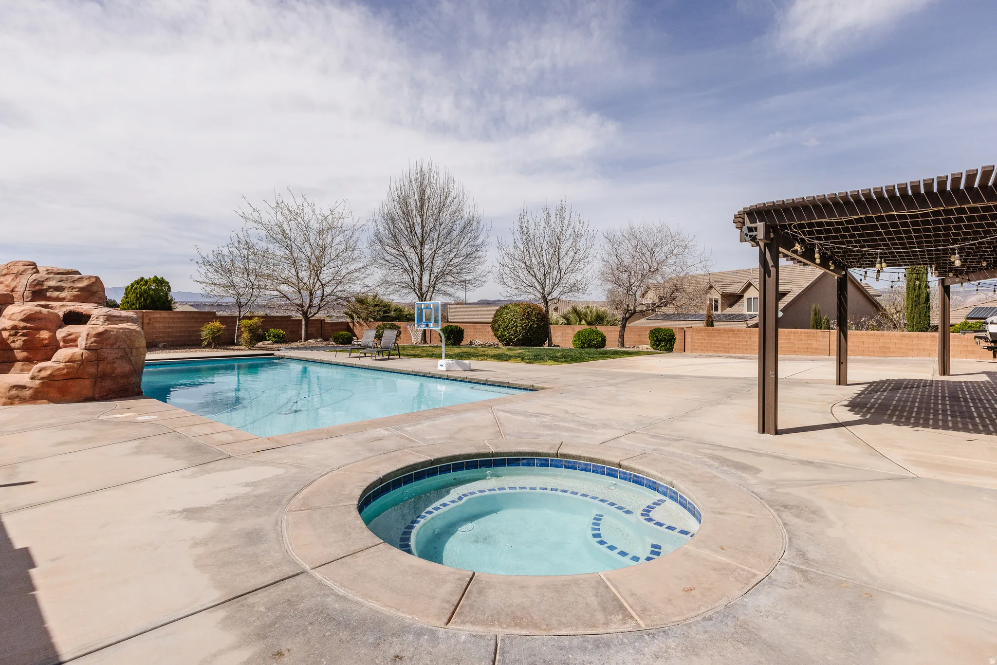 View of pool with a pergola, patio surround, an in-ground hot tub, and a fenced backyard