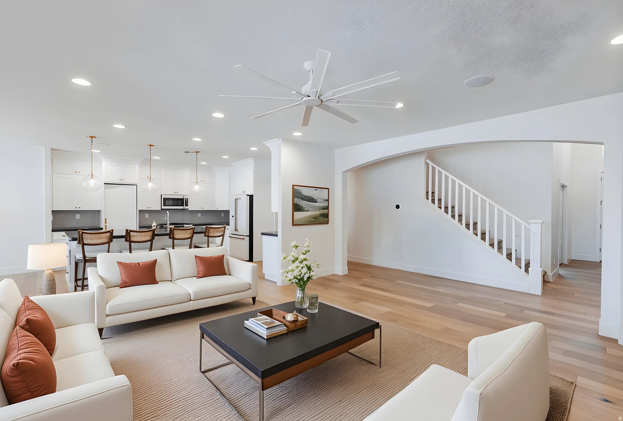 Living room featuring light wood finished floors, recessed lighting, arched walkways, and ceiling fan