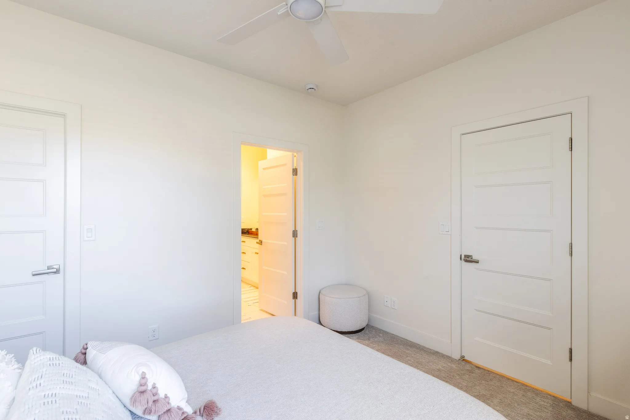 Bedroom featuring connected bathroom, light carpet, and ceiling fan