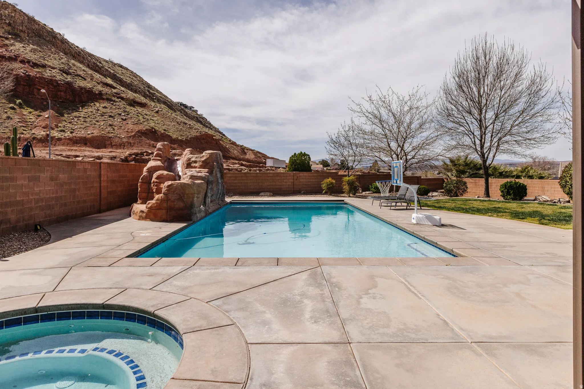 View of pool featuring patio surround, a fenced backyard, and an in-ground hot tub