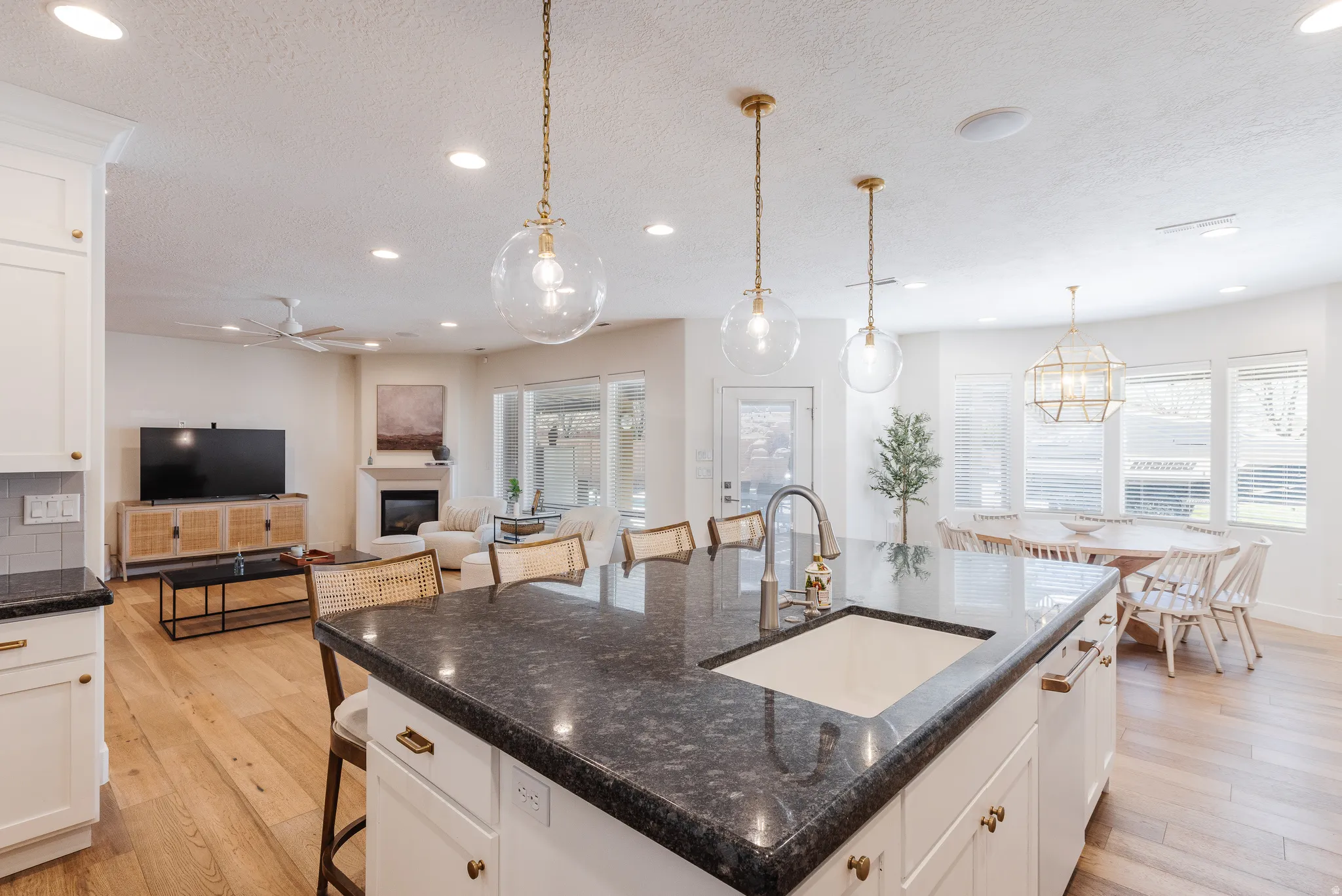 Kitchen featuring white cabinets, a breakfast bar, light wood-style floors, dark stone countertops, and a textured ceiling