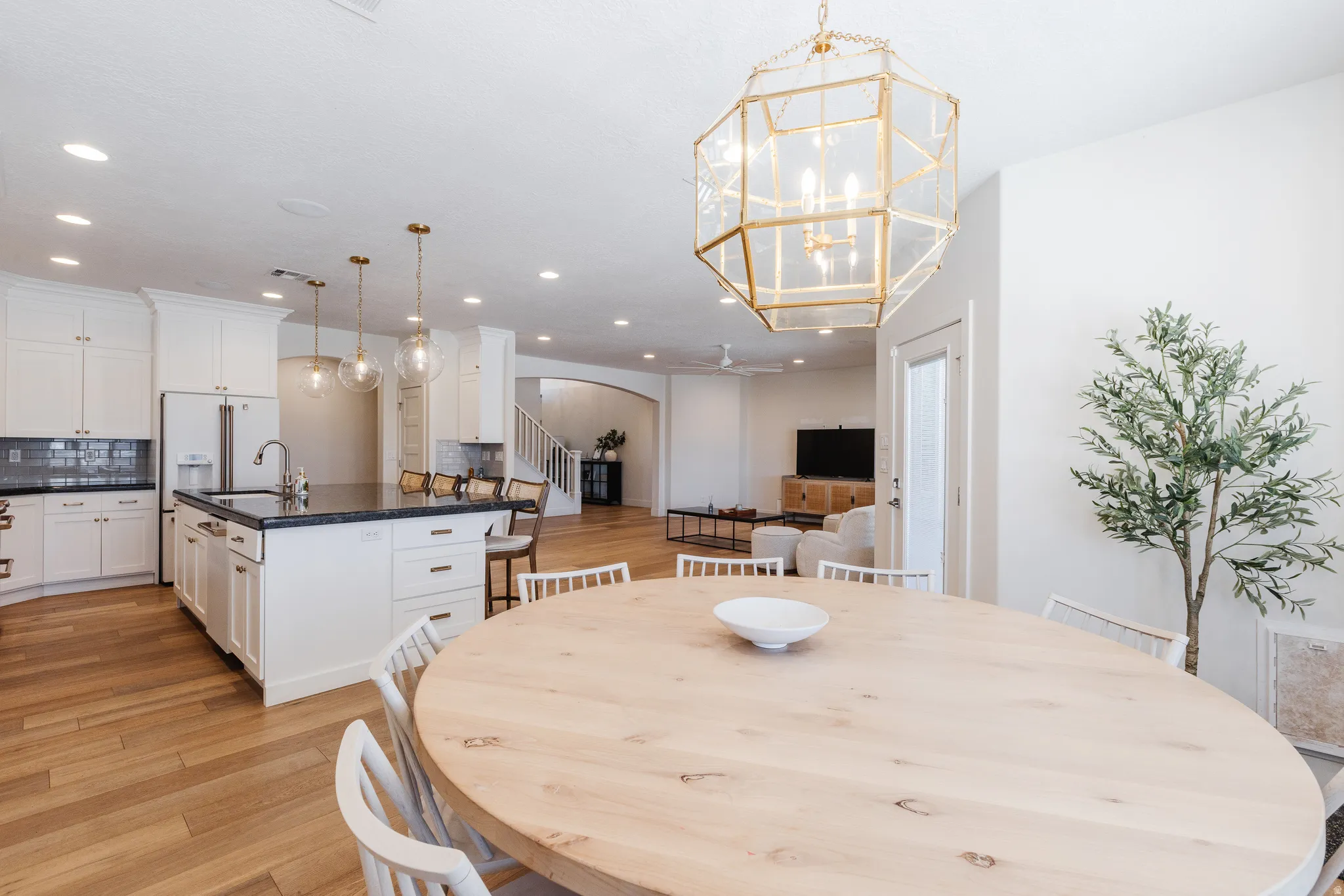Dining space with light wood-style floors, arched walkways, and hanging lights