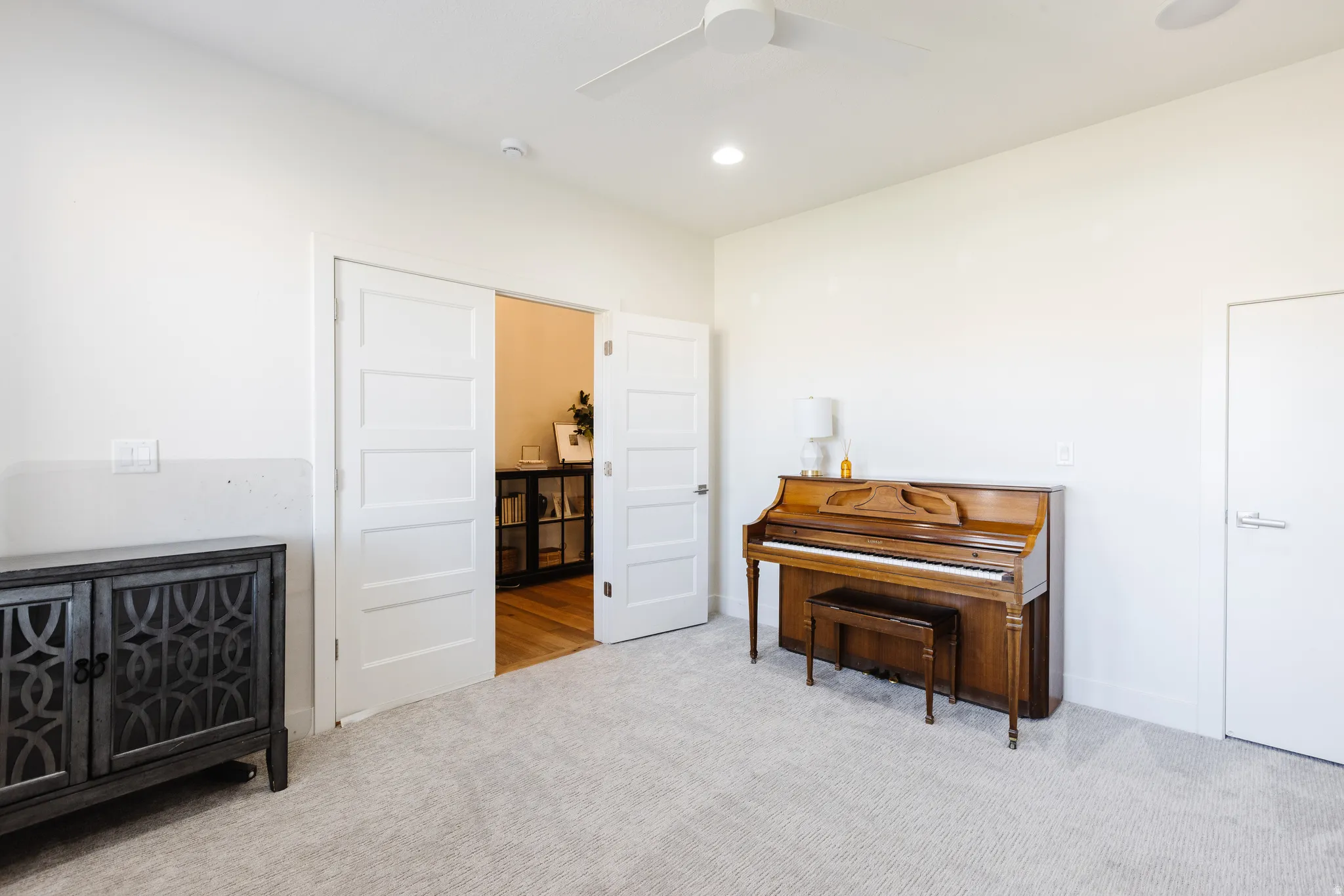 Living area with light carpet, a ceiling fan, and recessed lighting