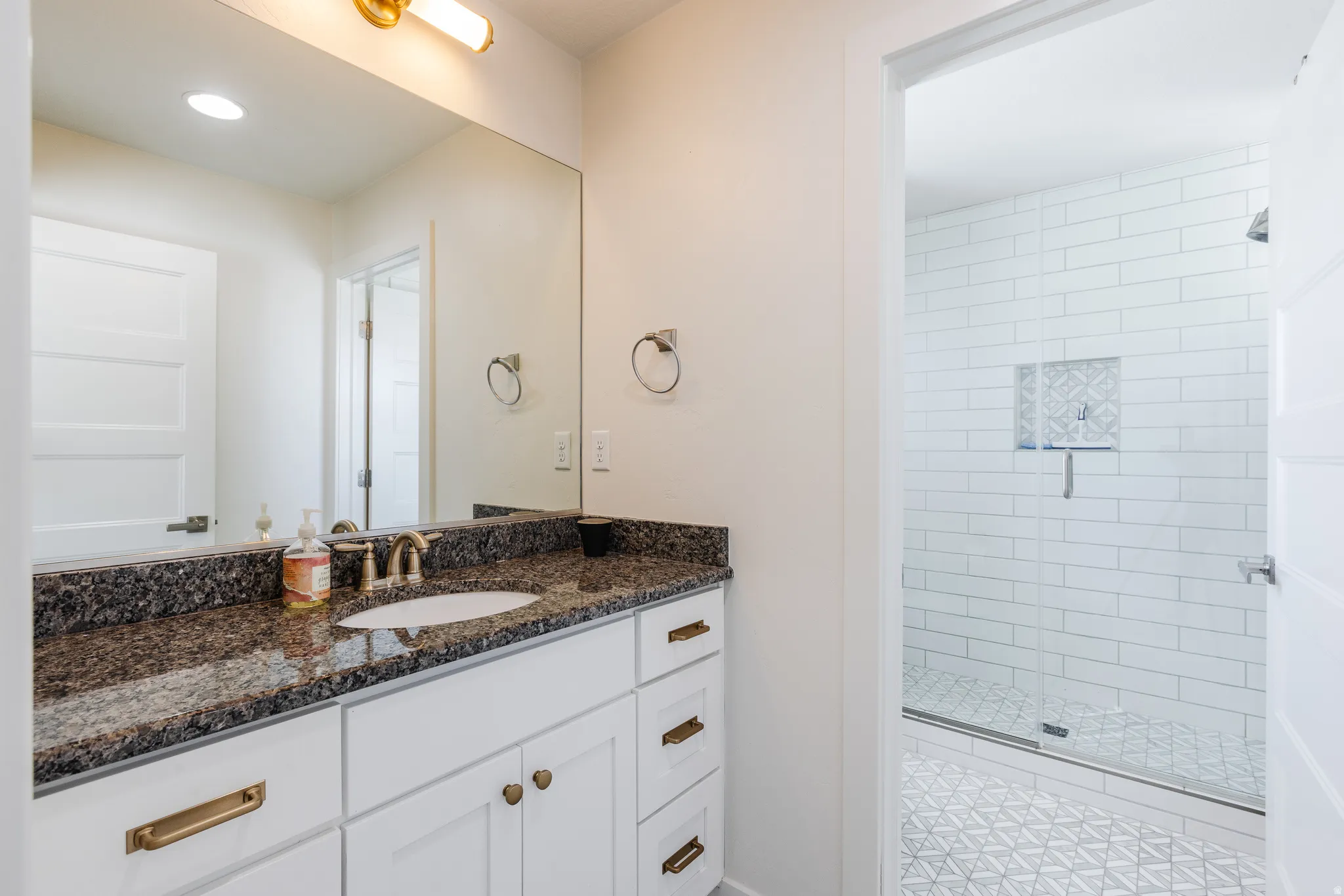Bathroom with a shower stall, vanity, and recessed lighting