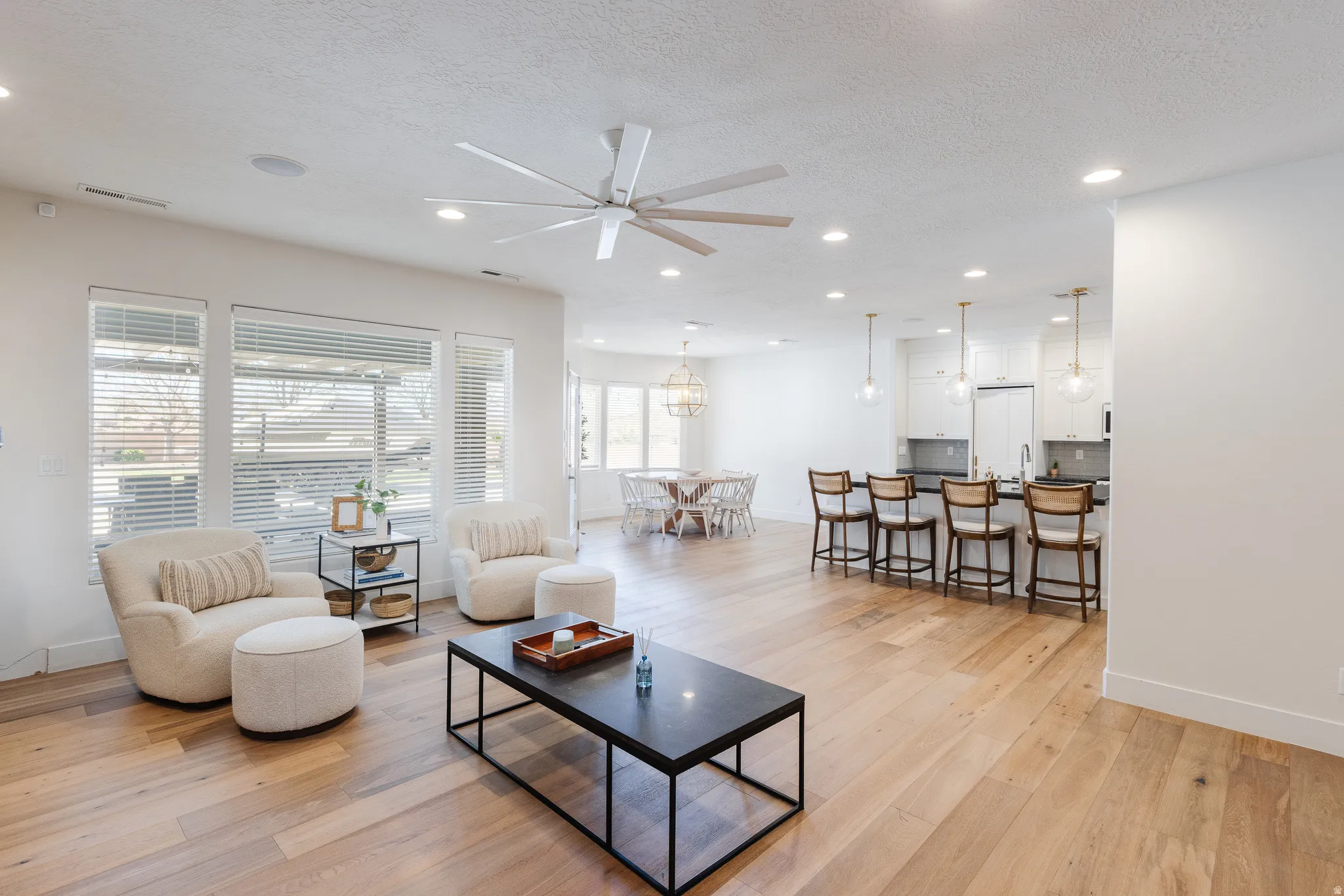 Living room with light wood-style flooring, ceiling fan, a textured ceiling, and recessed lighting