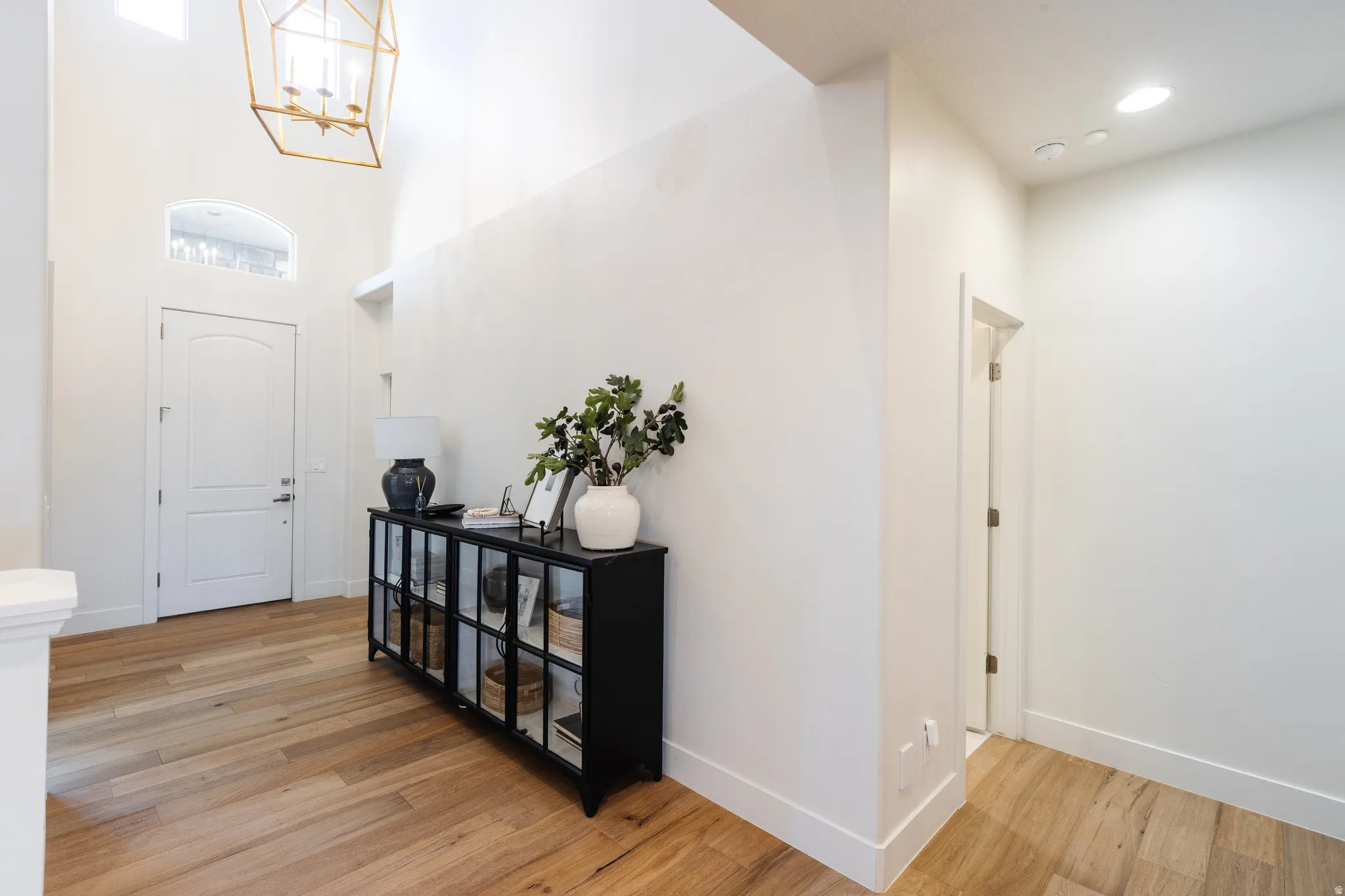 Entrance foyer with light wood-type flooring, hanging lights, and a high ceiling