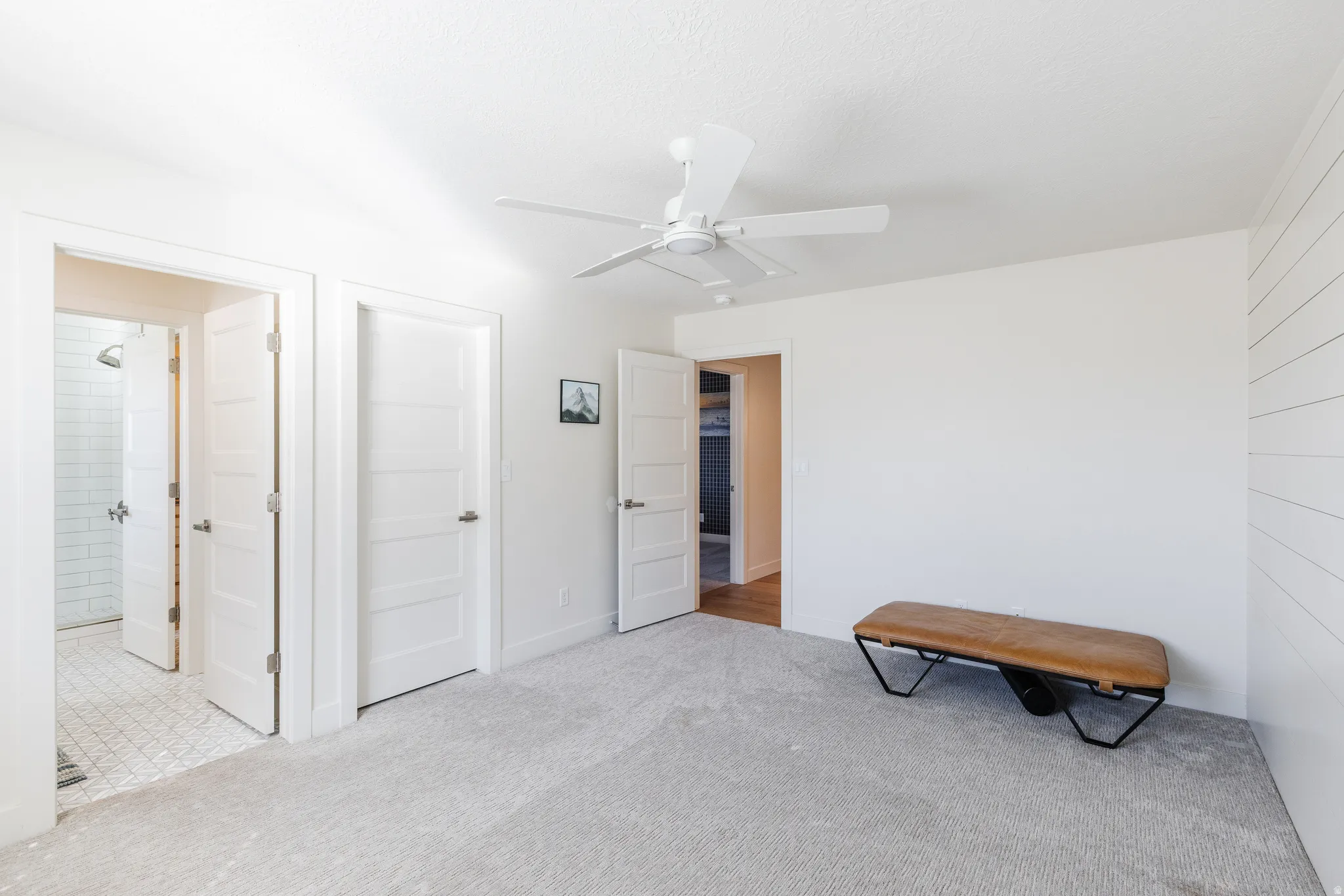 Bedroom with light colored carpet, ceiling fan, and ensuite bath