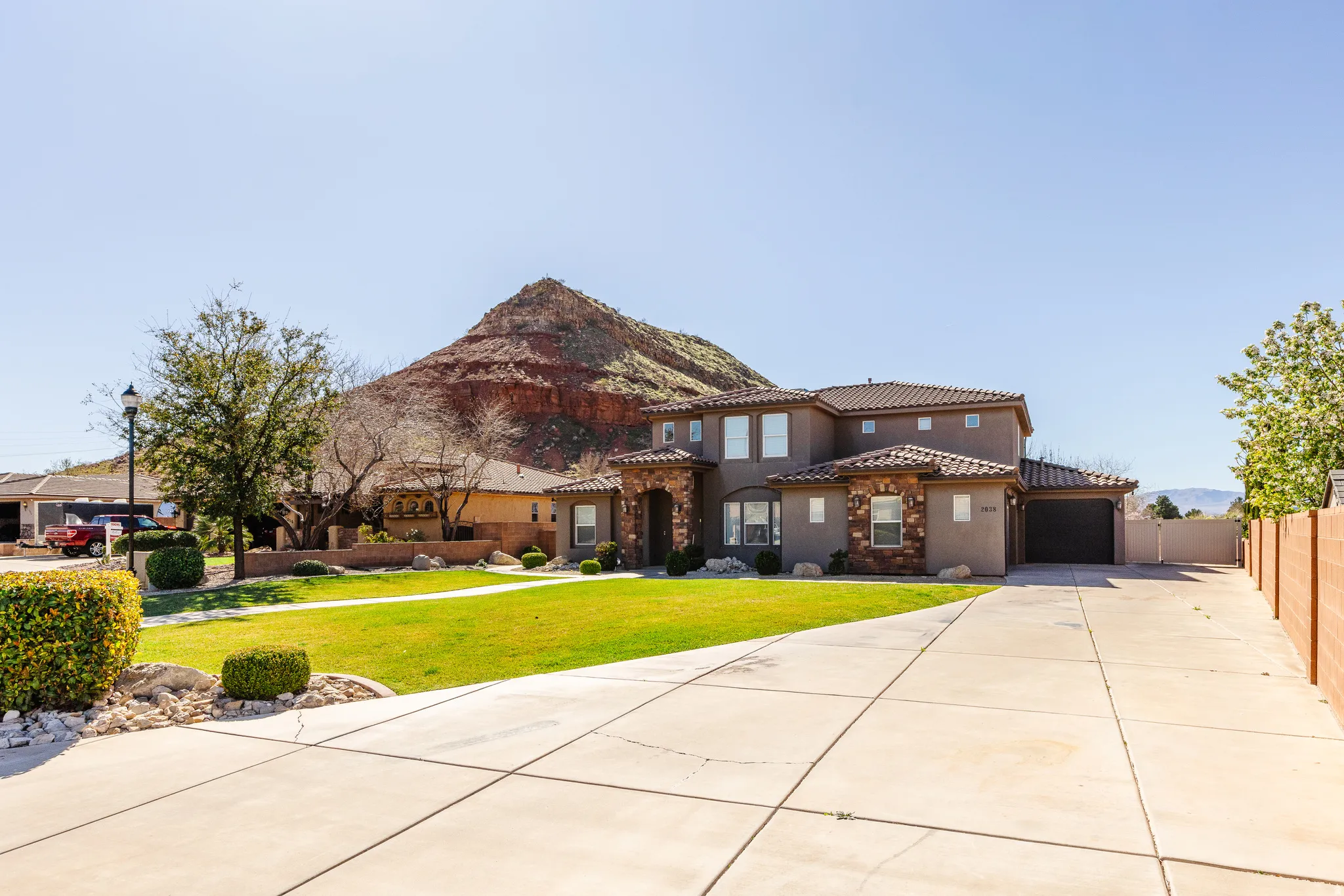 Mediterranean / spanish house featuring concrete driveway, a tiled roof, stucco siding, an attached garage, and stone siding