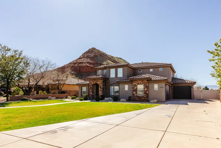 Mediterranean / spanish-style house with stucco siding, driveway, a front yard, an attached garage, and a tiled roof