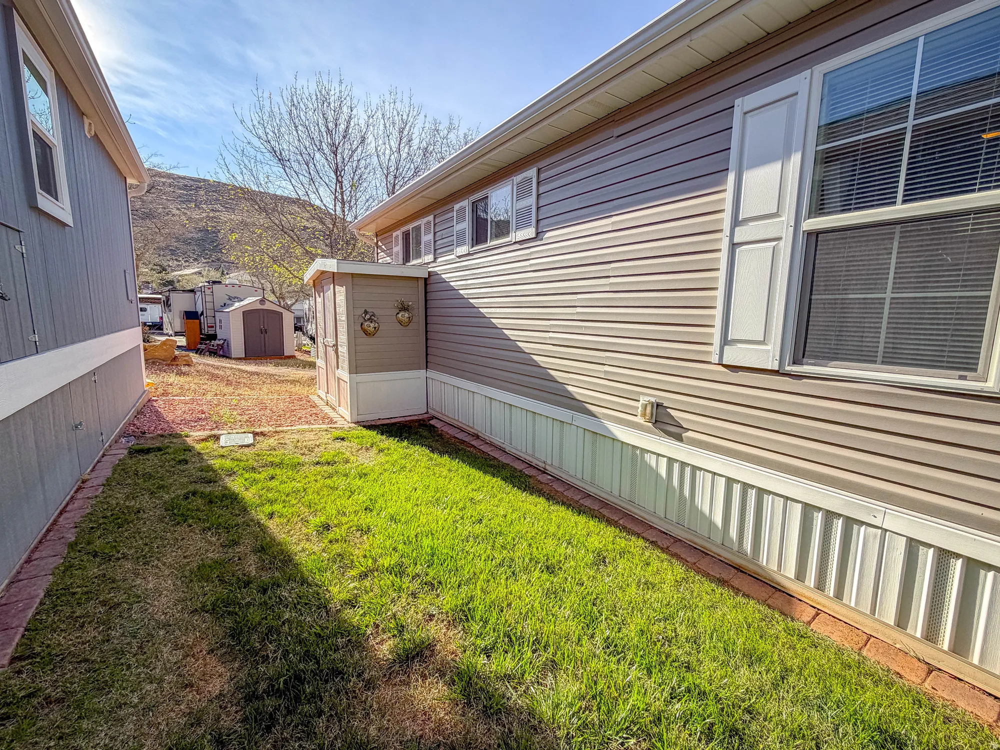 View of side of home featuring a storage shed and a lawn