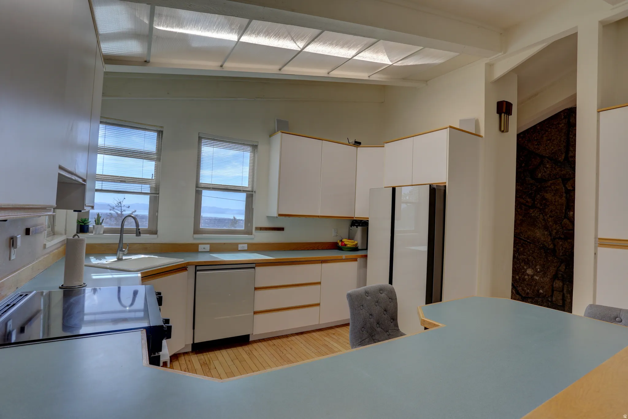 Kitchen with white cabinetry, range with electric cooktop, dishwasher, freestanding refrigerator, and light wood-style floors