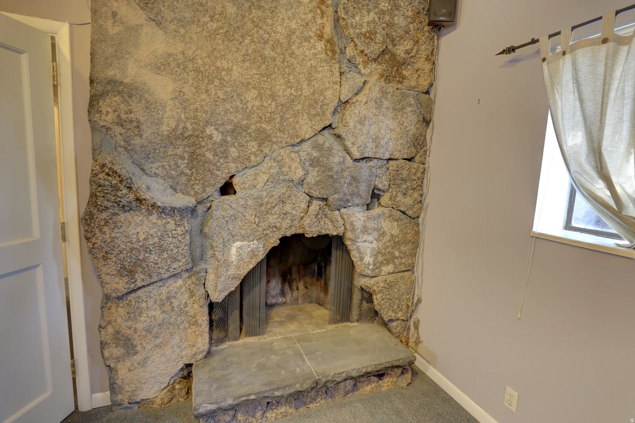 Detailed view of a stone fireplace and carpet flooring