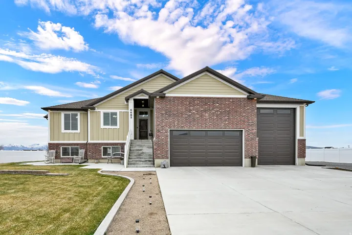 View of front of home with a garage, concrete driveway, a front lawn, and brick siding