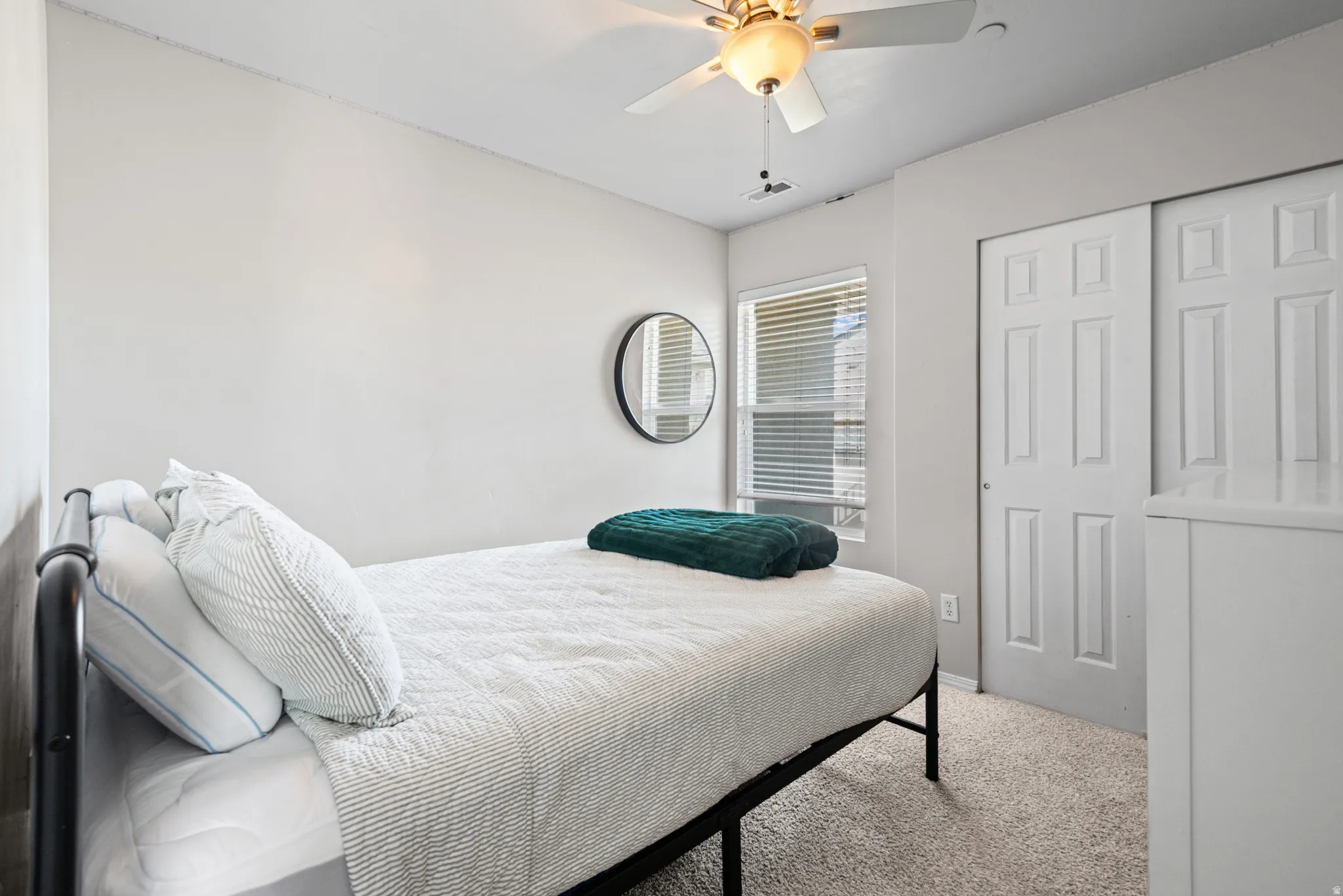 Bedroom with light carpet, ceiling fan, and a closet