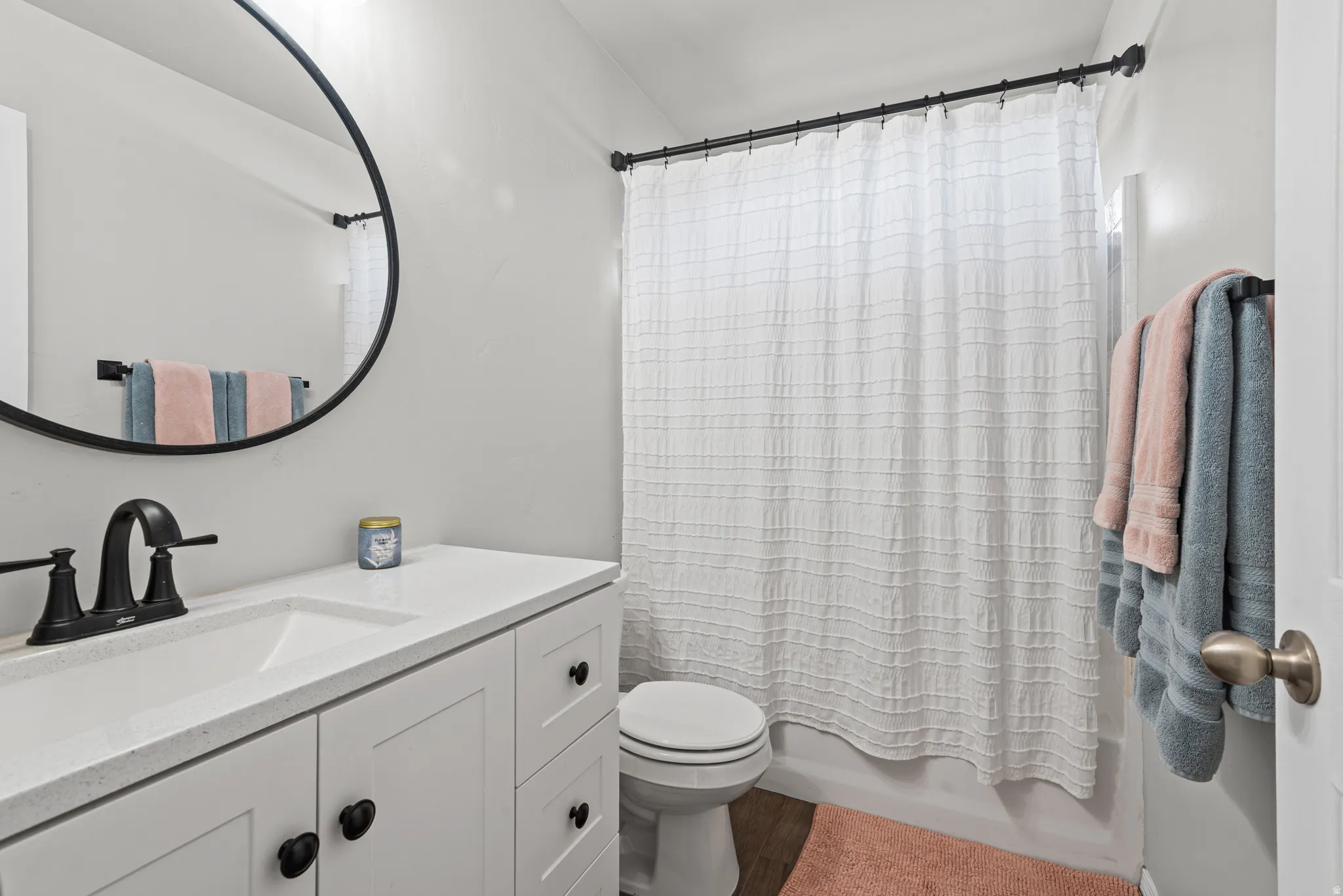 Bathroom with vanity, shower / bath combo with shower curtain, and wood finished floors