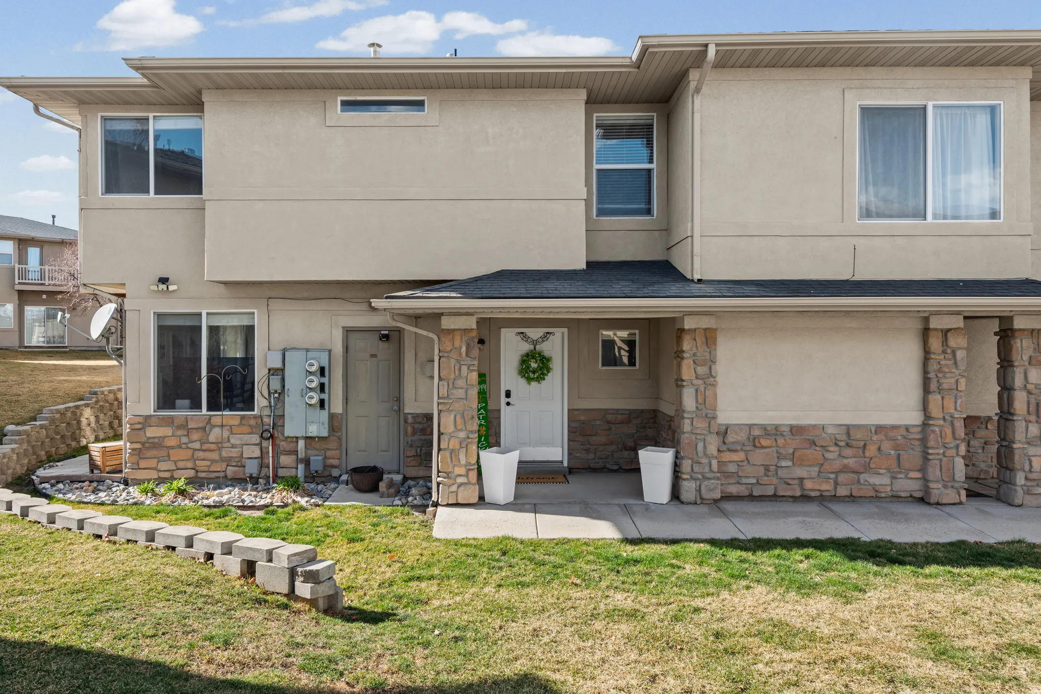 View of front of property featuring stone siding, stucco siding, and a front lawn
