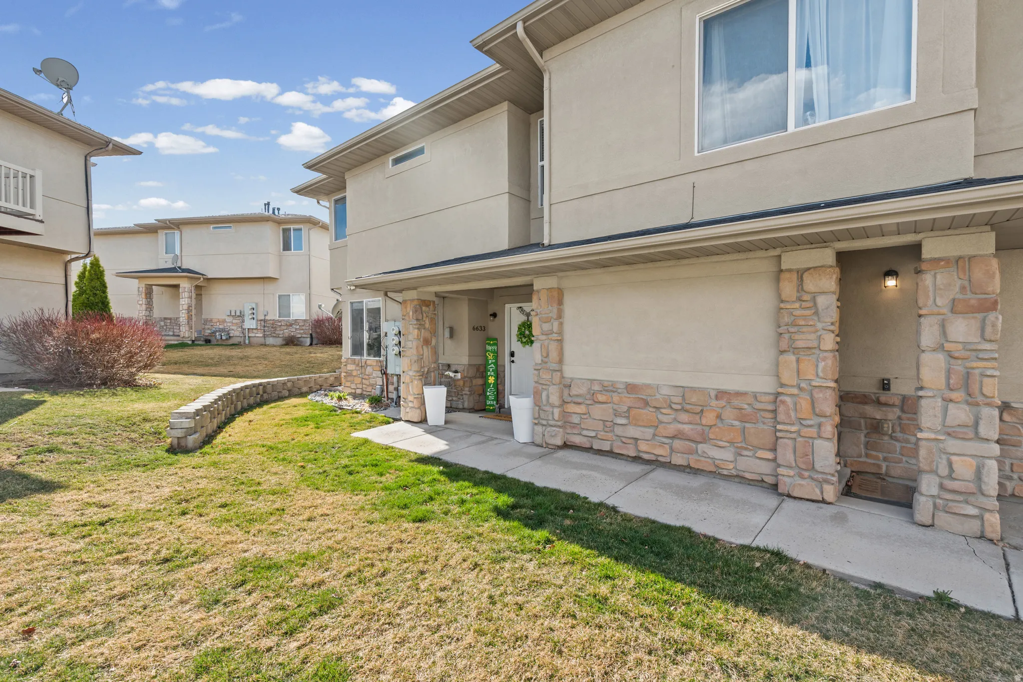 Property entrance with stucco siding, stone siding, and a yard