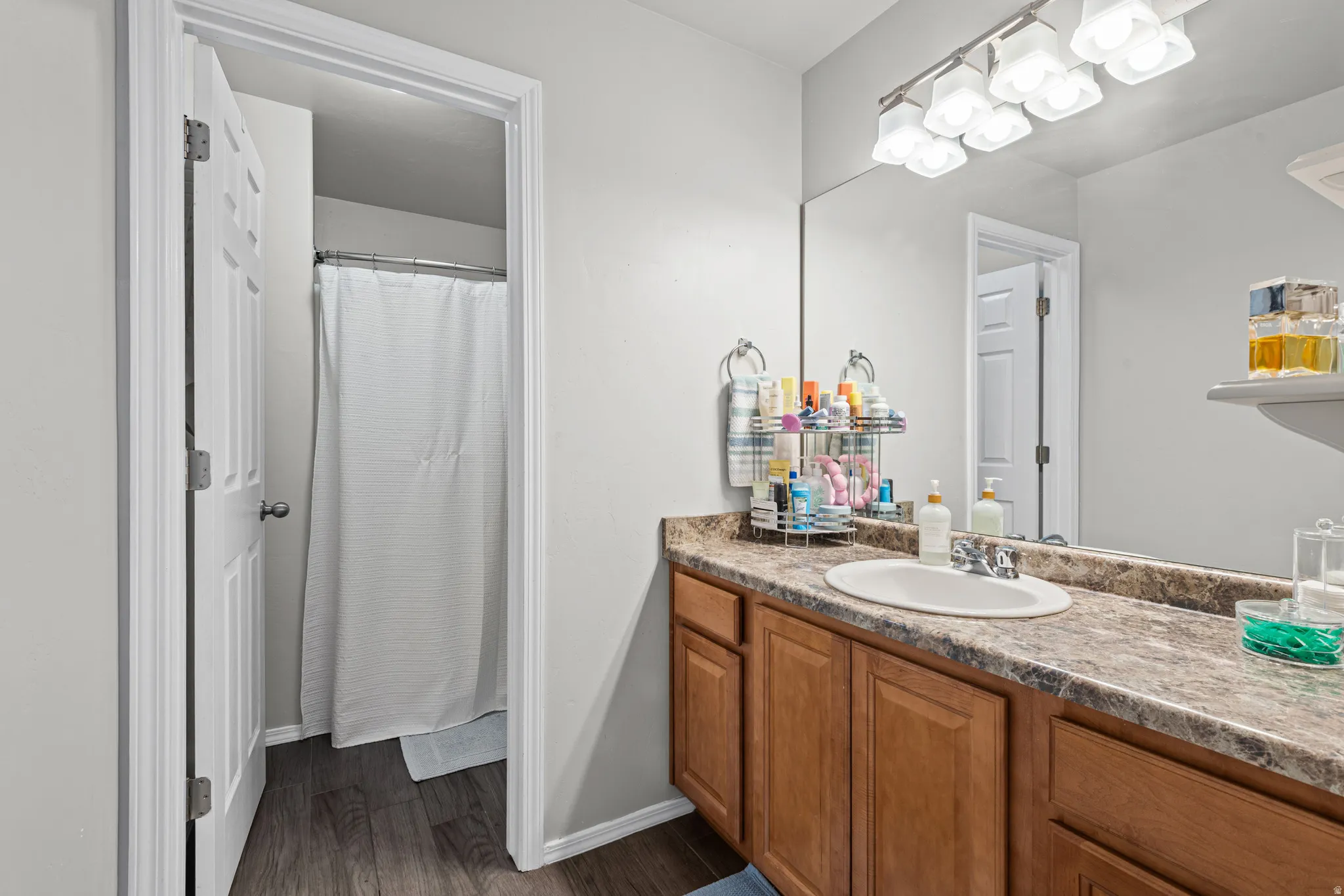 Bathroom featuring a shower with curtain, vanity, and dark wood-style floors