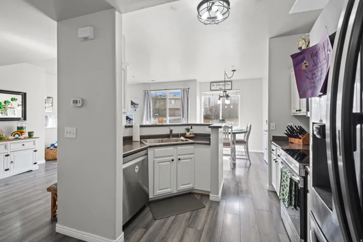 Kitchen featuring dark countertops, white cabinets, stainless steel appliances, and dark wood-type flooring