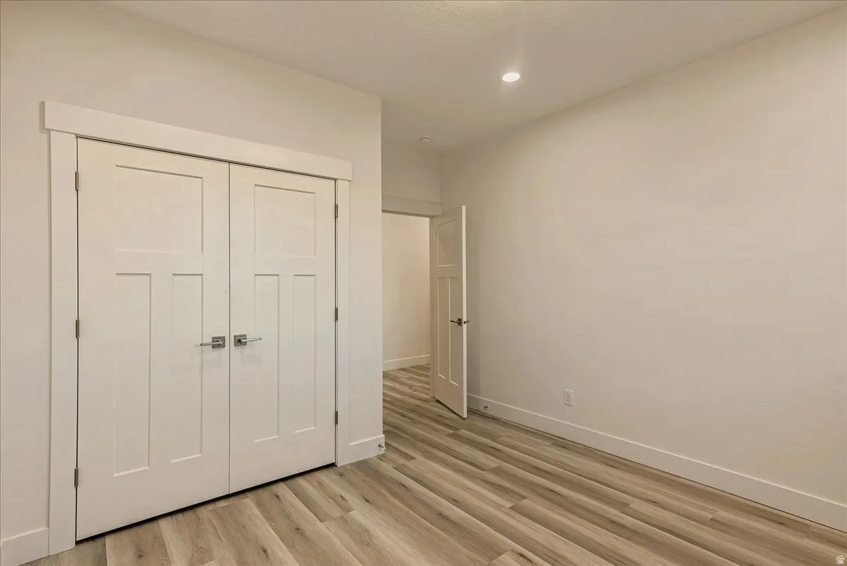 Unfurnished bedroom with a closet, light wood-style floors, and recessed lighting