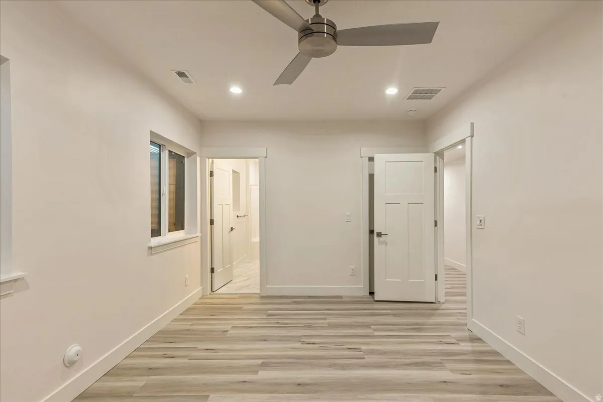 Unfurnished bedroom featuring light wood-style flooring, a ceiling fan, recessed lighting, and connected bathroom