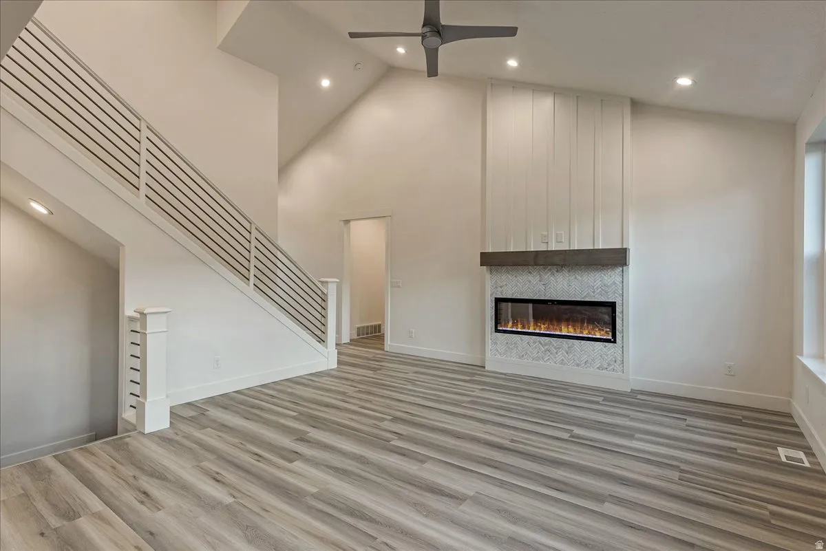 Unfurnished living room with light wood-style flooring, recessed lighting, a ceiling fan, vaulted ceiling, and a fireplace