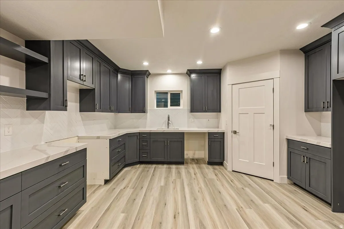 ADU Kitchen featuring light wood-style flooring, open shelves, recessed lighting, light stone countertops, and decorative backsplash