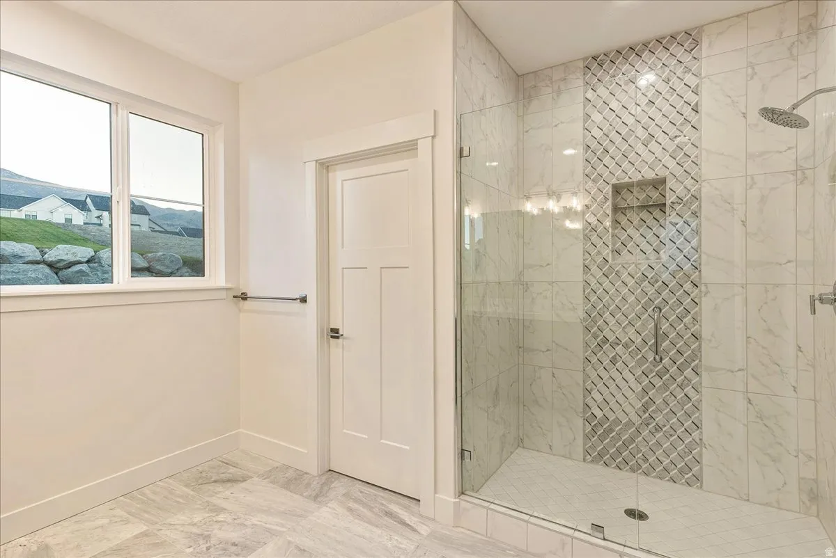 Primary bathroom featuring a marble finish shower and light marble finish flooring