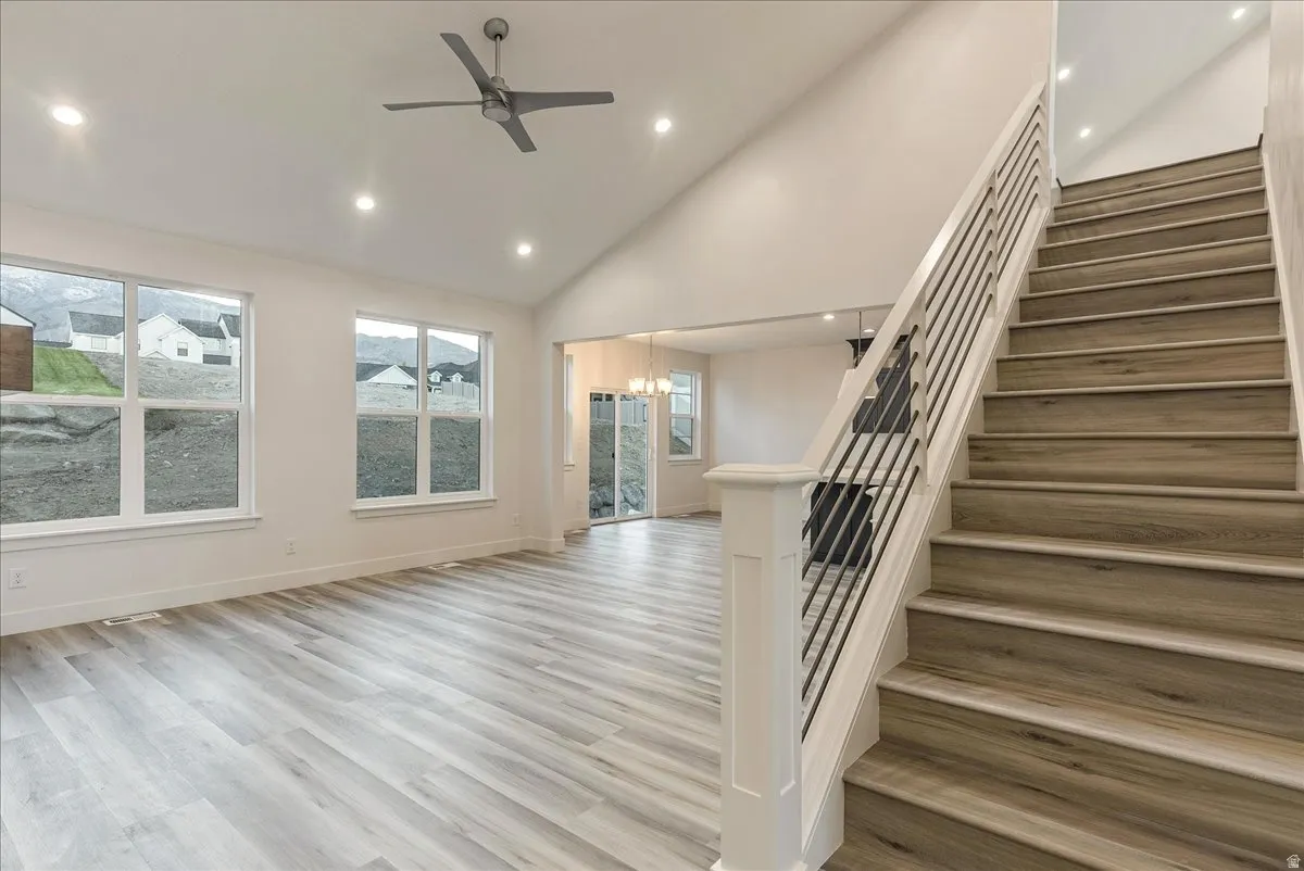 Stairway featuring a high ceiling, ceiling fan, wood finished floors, and a fan