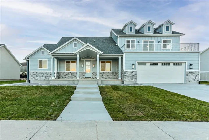 View of front of property featuring stone siding, covered porch, board and batten siding, and a front lawn