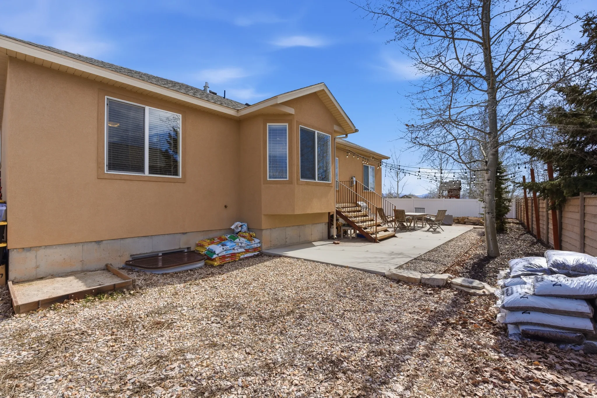Rear exterior featuring a stucco finish, ground-level patio, and exterior stairs leading to a second-story deck