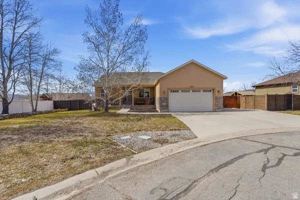 Ranch-style house featuring stucco siding, stone siding, an attached garage, and concrete driveway