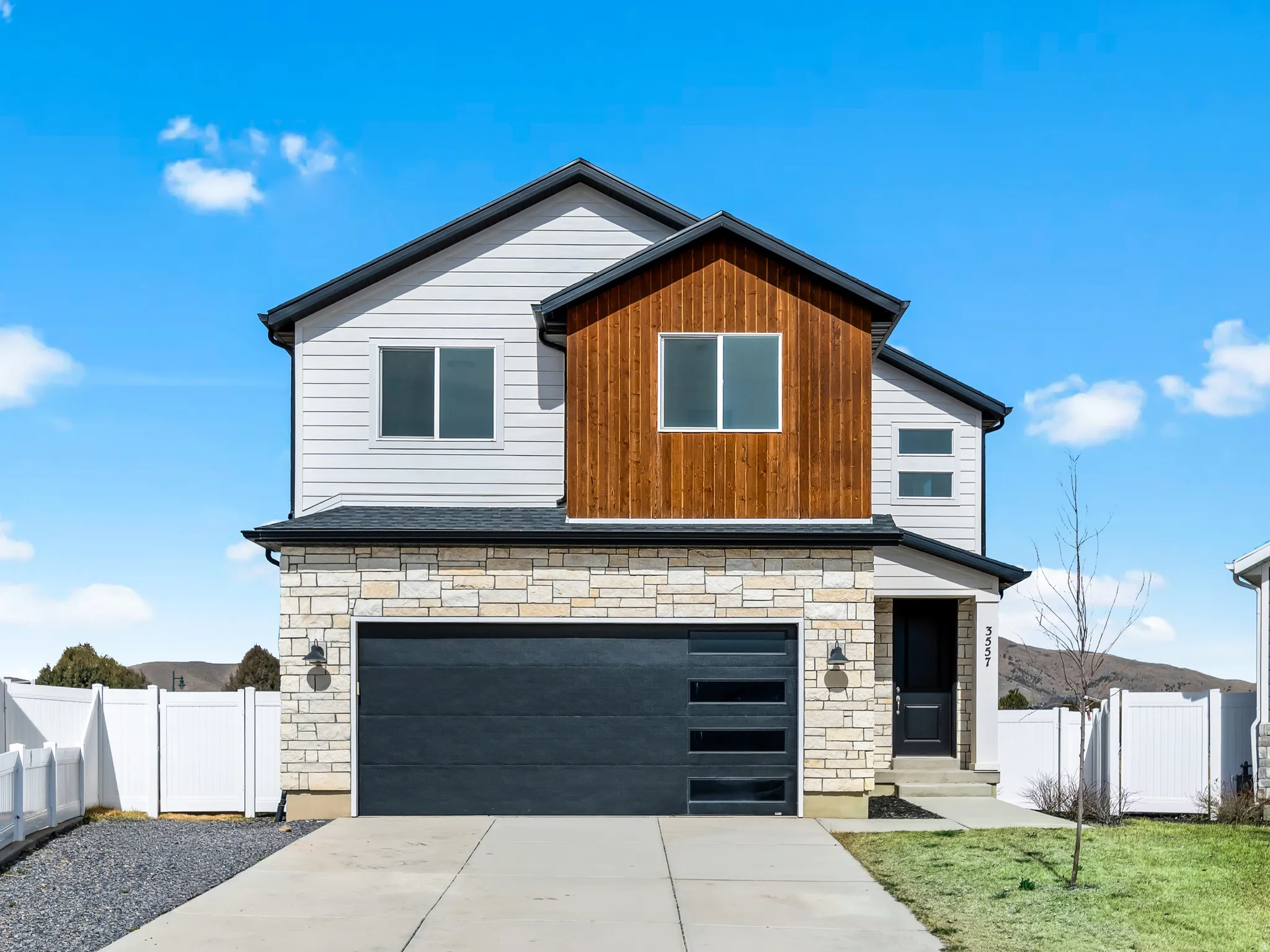 Contemporary house with stone siding, concrete driveway, an attached garage, and board and batten siding